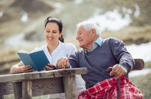 Hospice Patient and Caregiver Reading Together Outside
