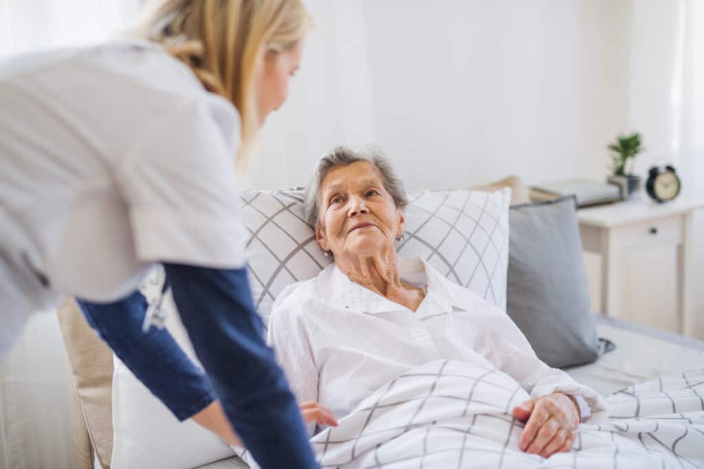 Hospice nurse assisting a hospice patient laying down