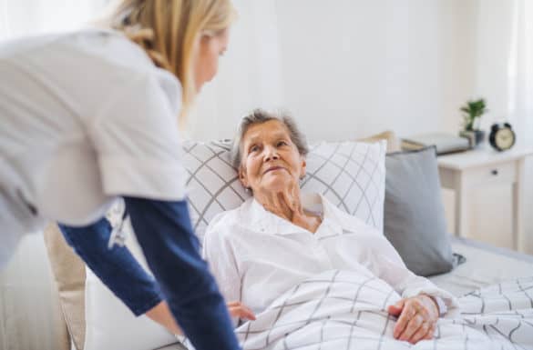 Hospice nurse assisting a hospice patient laying down